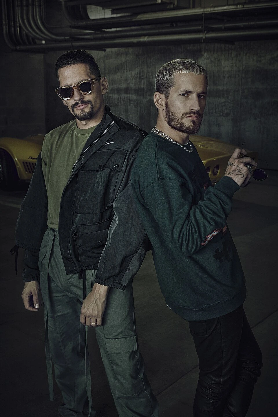Mau y Ricky posing together in a dark, editorial-style portrait